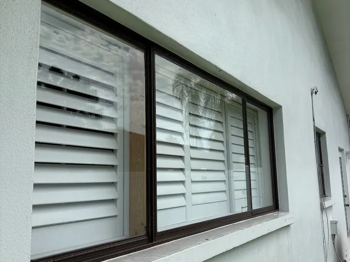 Streak-free dark-framed window with plantation shutters in Tampa