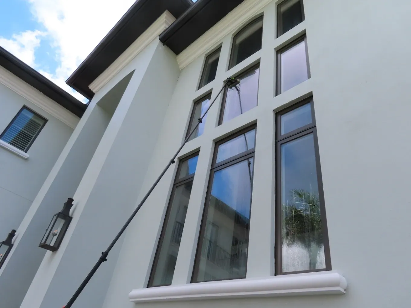 Water-fed pole cleaning a two-story window wall on a waterfront Tampa estate